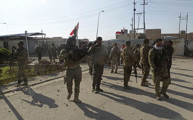 Iraqi security forces enter the government complex in central Ramadi, 70 miles (115 kilometers) west of Baghdad, Iraq, Monday, Dec. 28, 2015. Iraqi military forces on Monday retook a strategic government complex in the city of Ramadi from Islamic State militants who have occupied the city since May. (AP/Osama Sami)