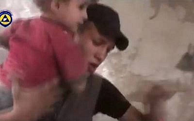 In this file image made from video posted online on Friday, Oct. 2, 2015, by Syrian Civil Defense, also known as the White Helmets, a volunteer search and rescue group, which has been verified and is consistent with other AP reporting, a paramedic rescues a child from the site of what witnesses said was a Russian airstrike in Douma, Syria. (Syria Civil Defense via AP video, File)