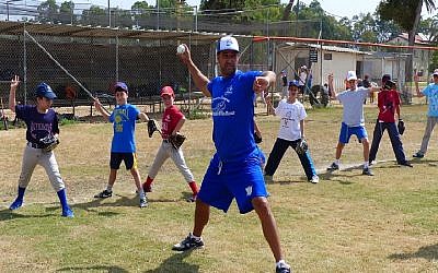 Nate Fish, director of the Israel Association of Baseball, demonstrating pitching to Israeli kids. (Margo Sugarman/IAB)