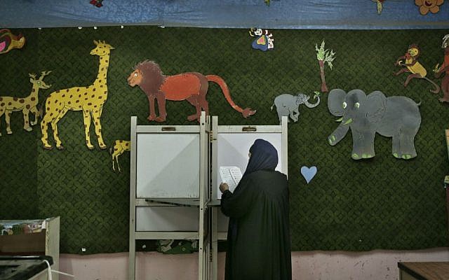In this Sunday, Nov. 22, 2015 file photo, a woman reads a ballot inside a polling station for women during the second phase of the parliamentary elections in Qalyoubiya governorate, north of Cairo, Egypt. (AP Photo/Nariman El-Mofty, File)