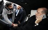 Turkish President Recep Tayyip Erdogan, right, takes Vezir Cakras by hand while speaking on his mobile phone inside his car stationed over the Bosporus Bridge in Istanbul, Friday, Dec. 25, 2015. Erdogan’s office says the Turkish president has talked Cakras out of jumping off a bridge to commit suicide. (Yasin Bulbul/Presidential Press Service Pool via AP Photo)