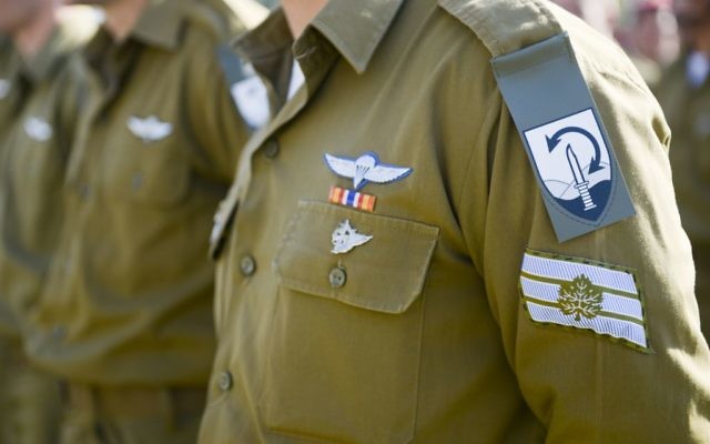 The new unit insignia for the Commando Brigade -- a knife on a background of mountains with a two-sided arrow signifying the unit's overseas reach -- is unveiled in a ceremony on December 27, 2015. (Yahav Trudler/IDF Spokesperson's Unit)