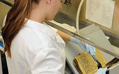 An expert in the US restoring one of the books rescued from the Iraqi Jewish community in Baghdad. (Courtesy: US National Archives and Records Administration)