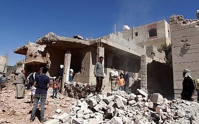 Yemeni men walk past a building, damaged during an air-strike by the Saudi-led coalition, in the capital Sanaa on November 29, 2015. (AFP Photo/Mohammed Huwais)