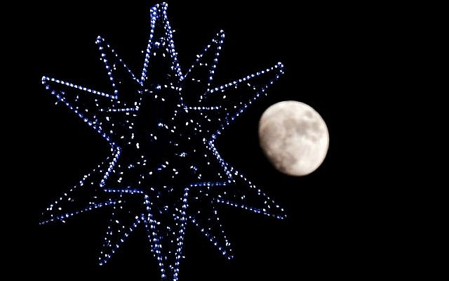 The moon rises behind the star of a Christmas Tree in central Rome on December 22, 2015. (AFP/TIZIANA FABI) The moon rises behind the star of a Christmas Tree in central Rome on December 22, 2015. (AFP/TIZIANA FABI)