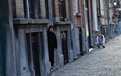 A woman stepping out of an apartment building in the Brussels district of Schaerbeek, January 8, 2016. Belgian police have found three belts for possible use in suicide attacks, traces of explosives, and a fingerprint of wanted Paris attacks suspect Salah Abdeslam at the site, prosecutors said. (AFP/Emmanuel Dunand)