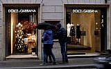 People stand in front of a Dolce e Gabana shop window in downtown Rome's Via Condotti, January 8, 2016. (AFP/FILIPPO MONTEFORTE)