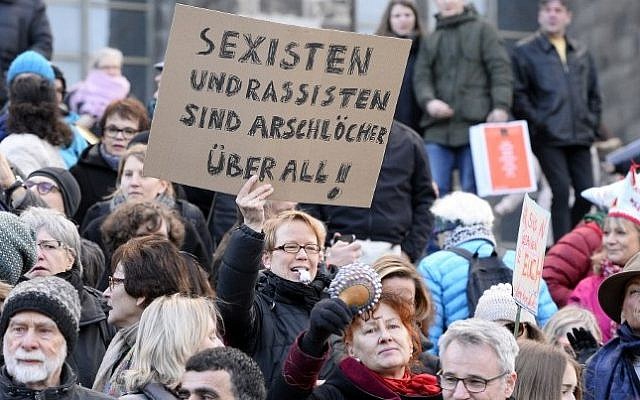 A woman holds up a sign reading "Sexists and racists are assholes-everywhere" while taking part in a demonstration against violence against women in front of the cathedral in Cologne, western Germany, on January 9, 2015 (Roberto Pfeil/AFP) A woman holds up a sign reading "Sexists and racists are assholes-everywhere" while taking part in a demonstration against violence against women in front of the cathedral in Cologne, western Germany, on January 9, 2015 (Roberto Pfeil/AFP)