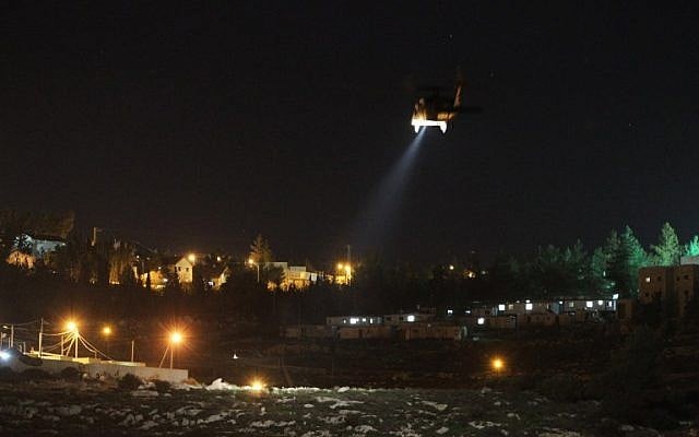 A picture taken from the Palestinian village of Dahriya, shows an Israeli army helicopter flying over the Otniel settlement in the southern West Bank as security forces search for a Palestinian suspected of stabbing to death Dafna Meir, a 40-year-old Israeli mother, at her home on January 17, 2016. (AFP/HAZEM BADER)