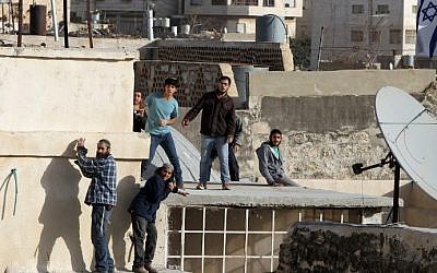 Jewish settlers stand on the roof of a building after entering two homes in the center of Hebron on January 21, 2016. (AFP/Hazem Bader)