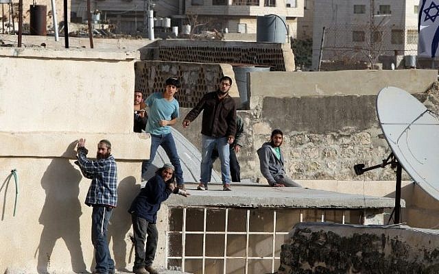 Jewish settlers stand on the roof of a building after entering two homes in the center of Hebron on January 21, 2016. (AFP/Hazem Bader) Jewish settlers stand on the roof of a building after entering two homes in the center of Hebron on January 21, 2016. (AFP/Hazem Bader)