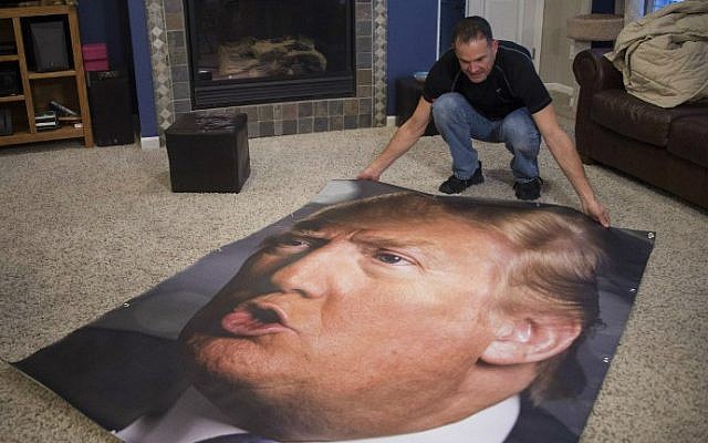 George Davey, a supporter of Republican presidential candidate Donald Trump, unrolls a back-up poster of Trump in his living room, which would replace the large poster of Trump he has on display on his backyard fence if it is vandalized, in West Des Moines, Iowa, January 25, 2016, ahead of the Iowa Caucus. (Jim Watson/AFP) George Davey, a supporter of Republican presidential candidate Donald Trump, unrolls a back-up poster of Trump in his living room, which would replace the large poster of Trump he has on display on his backyard fence if it is vandalized, in West Des Moines, Iowa, January 25, 2016, ahead of the Iowa Caucus. (Jim Watson/AFP)