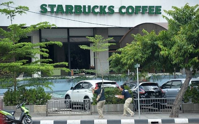 Plainclothes police aim their handguns towards suspects outside a cafe after a series of blasts hit the Indonesia capital Jakarta on January 14, 2016. (AFP PHOTO / Bay ISMOYO)