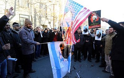 Iranian men burn Israeli and American flags during a demonstration against the execution of prominent Shiite Muslim cleric Nimr al-Nimr by Saudi authorities, on January 3, 2016, outside the Saudi embassy in Tehran. (AFP PHOTO / ATTA KENARE)
