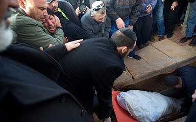 The family and friends of 30-year-old Tel Aviv shooting victim Shimon Ruimi, mourns as his body is lowered into the grave during his funeral in the southern town of Ofakim on January 3, 2016. (AFP PHOTO/MENAHEM KAHANA) 