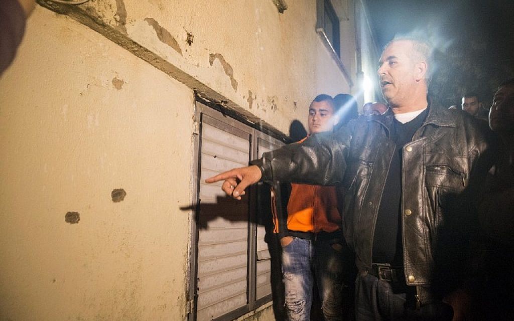 A man points out at bullet holes at the site where Israeli special forces shot Nashat Milhem, who murdered three people in a Tel Aviv shooting spree last week, in the  northern town of Arara, on January 8, 2016. (AFP PHOTO/JACK GUEZ)