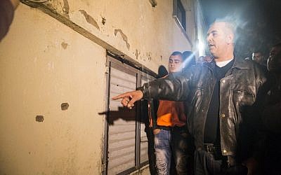 A man points out at bullet holes at the site where Israeli special forces shot Nashat Milhem, who murdered three people in a Tel Aviv shooting spree last week, in the northern town of Arara, on January 8, 2016. (AFP PHOTO/JACK GUEZ) 