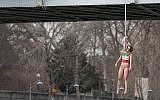 An activist hangs from a noose-like rope from a Paris bridge to call attention to the large number of executions in Iran,  January 28, 2016. (AP Photo/Zacharie Scheurer)