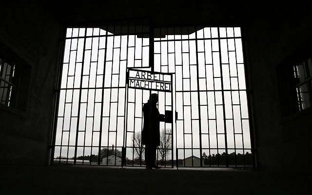A man enters the Sachsenhausen Nazi death camp through the gate below the phrase 'Arbeit macht frei' (work sets you free) on International Holocaust Remembrance Day, Jan. 27, 2016, in Oranienburg near Berlin, Germany. (AP Photo/Markus Schreiber)
