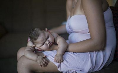 Gleyse Kelly da Silva holds her daughter Maria Giovanna as she sleeps in their house in Recife, Pernambuco state, Brazil, Wednesday, Jan. 27, 2016. (AP Photo/Felipe Dana)