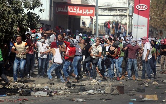 Palestinian protesters throw stones at Israeli security forces at the Hawara checkpoint, south of the West Bank city of Nablus, October 11, 2015. (Flash90) Palestinian protesters throw stones at Israeli security forces at the Hawara checkpoint, south of the West Bank city of Nablus, October 11, 2015. (Flash90)