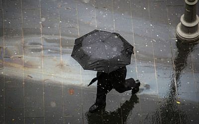 People walk with umbrellas in central Jerusalem as light snow begins to fall, January 25, 2016. (Hadas Parush/Flash90)