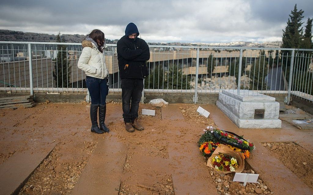 Mourners stand near the fresh grave of Shlomit Krigman, 23, after her funeral in Jeursalem on January 26, 2016 (Yonatan Sindel/Flash90)
