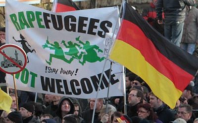 Right-wing demonstrators hold a sign reading "Rapefugees not welcome - Stay away!" and a sign with a crossed-out mosque as they march in Cologne, Germany, Saturday, January 9, 2016. (AP /Juergen Schwarz)