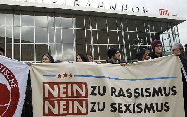 People protest in front of the main station in Cologne, Germany, on Wednesday, Jan. 6, 2016, holding a poster that reads: "No to Racism, No to Sexism" following mass sexual assaults at the site on New Year's Eve by purportedly "Arab-looking men." (AP Photo/Hermann J. Knippertz)