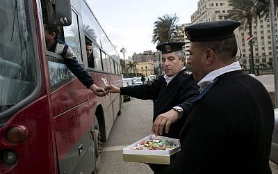 Egyptian policemen give out chocolates to citizens marking Police Day, which falls on Jan. 25, the anniversary of the 2011 uprising that toppled longtime ruler Hosni Mubarak in Tahrir Square, Cairo, Egypt on Jan. 24, 2016. (AP Photo/Roger Anis)