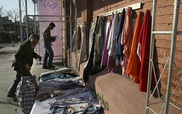 In this Thursday, Jan. 7, 2016 photo, Iranian men hang clothes on an outdoor charity wall in downtown Tehran, Iran. (AP Photo/Vahid Salemi) In this Thursday, Jan. 7, 2016 photo, Iranian men hang clothes on an outdoor charity wall in downtown Tehran, Iran. (AP Photo/Vahid Salemi)
