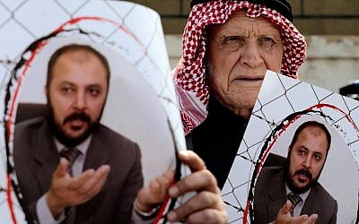 Supporters of Zaki Bani Irsheid, a top leader of the Muslim Brotherhood opposition group, hold photos of him, outside the state security court in Amman, Jordan, February 15, 2015. (AP Photo/Raad Adayleh)