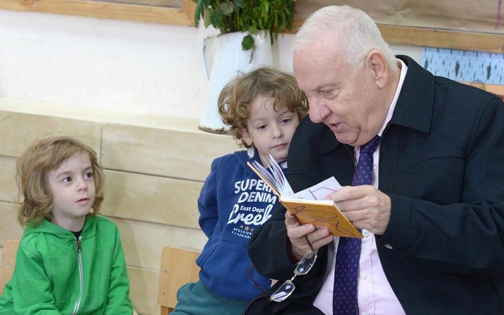 President Reuven Rivlin reading a book to the children at Hadas Kindergarten, on Sunday, January 3 2016. (Mark Neyman/GPO)