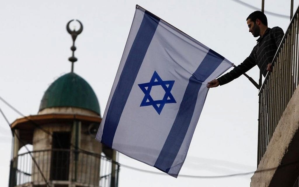 A Jewish-Israeli raising the Israeli flag near the Old City of Jerusalem, which has seen an influx of Jewish residents in predominantly Arab areas. (Abir Sultan/Flash 90) A Jewish-Israeli raising the Israeli flag near the Old City of Jerusalem, which has seen an influx of Jewish residents in predominantly Arab areas. (Abir Sultan/Flash 90)