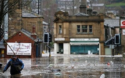 A man wades through flood waters at Hebden Bridge in West Yorkshire, England. (Peter Byrne/PA via AP)
