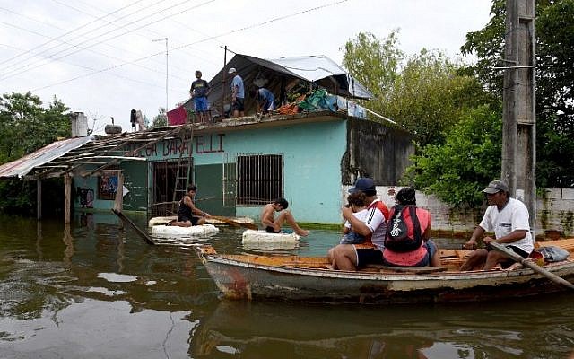 Local residents navigate along a flooded street in Asuncion, on January 4, 2016. So far, six people have died, more than 100,000 people have been displaced, 25,766 families are in shelters, 125,000 homes are without electric power. (AFP PHOTO/NORBERTO DUARTE) Local residents navigate along a flooded street in Asuncion, on January 4, 2016. So far, six people have died, more than 100,000 people have been displaced, 25,766 families are in shelters, 125,000 homes are without electric power. (AFP PHOTO/NORBERTO DUARTE)