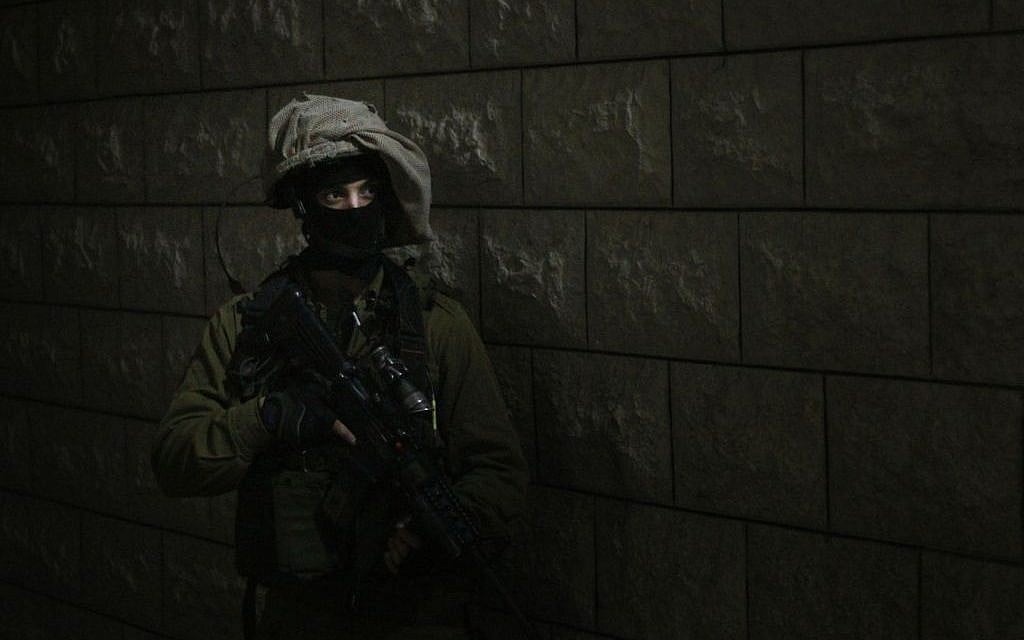 A soldier prepares to enter the home of a Palestinian teenager accused of throwing rocks at IDF troops during a riot in Qalqilya. An advance team had already entered the home to wake up the family, who initially denied that their son was home, on January 14, 2016. (Judah Ari Gross/Times of Israel)