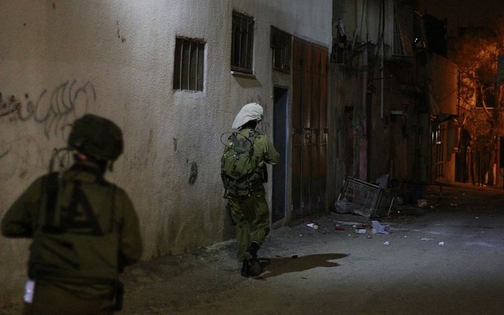 IDF soldiers move toward the home of two Palestinian teenagers who are believed to have taken part in violent protests in Qalqilya. An Arabic-speaking representative of the Defense Ministry's Coordinator of Government Activities in the Territories unit accompanies the battalion to facilitate conversation between the soldiers and the families of the accused on January 14, 2016. (Judah Ari Gross/Times of Israel)