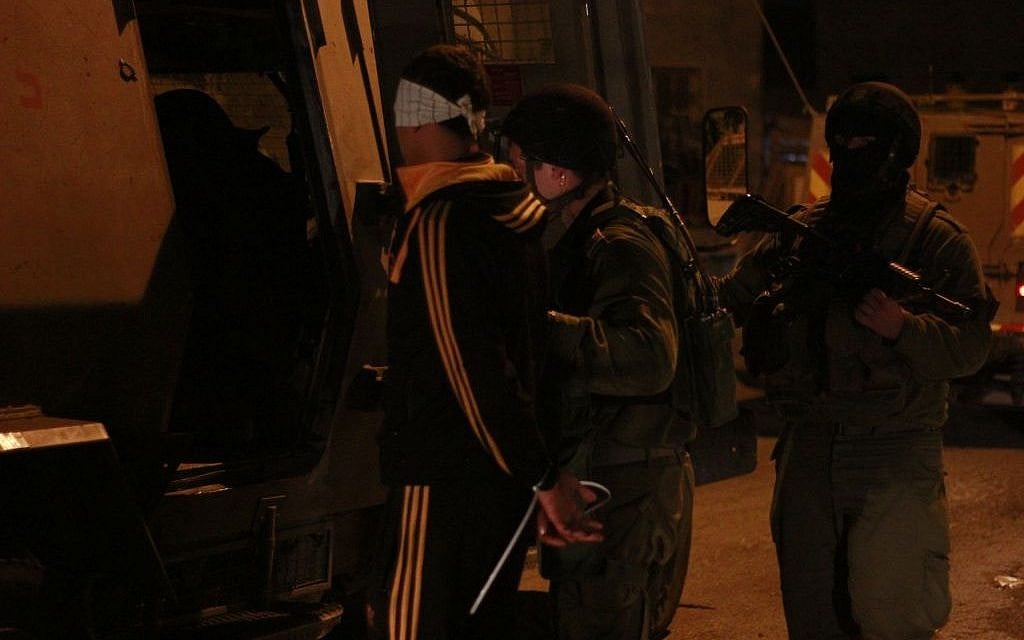 Soldiers load one of the suspects into the back of a Ze'ev, a large armored personnel carrier, in Qalqilya on January 14, 2016. The soldiers' commander, Lt. Col. Nimrod Cibulski, had them move the Palestinian teenager away from his family before blindfolding him and putting zip-ties on his wrists, in order to spare the suspect's father the sight of his son in restraints, Cibulski said. (Judah Ari Gross/Times of Israel)