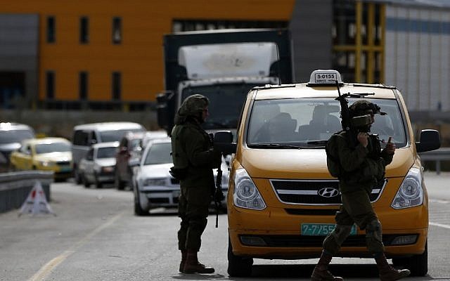 File: An Israeli soldier checks the documents of the Palestinian passengers of a taxi on their way out of Ramallah on February 1, 2016. (AFP/Abbas Momani)