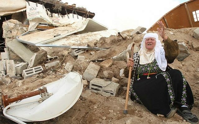 A Palestinian woman sits next to the remains of her home after it was demolished by Israeli bulldozers in a disputed military zone in the area of Musafir Jenbah, south of the West Bank town of Hebron, on February 2, 2016. (AFP/Hazem Bader)