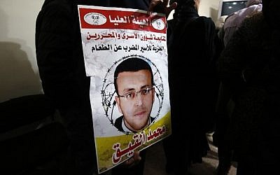 A supporter of hunger striking Palestinian prisoner Mohammed al-Qiq holds a portrait as he demonstrates in solidarity with him on February 7, 2016, outside the International Committee of the Red Cross (ICRC) offices in the West Bank city of Ramallah. (AFP / ABBAS MOMANI)