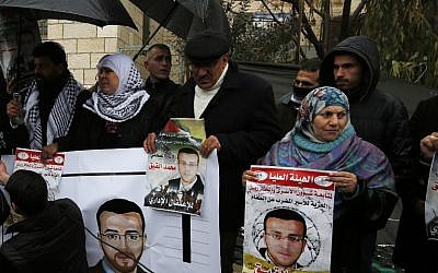 Supporters of hunger-striking Palestinian prisoner Mohammed al-Qiq hold portraits as they demonstrate in solidarity with him outside the offices of the International Committee of the Red Cross near the West Bank city of Ramallah, February 7, 2016. (AFP/Abbas Momani)