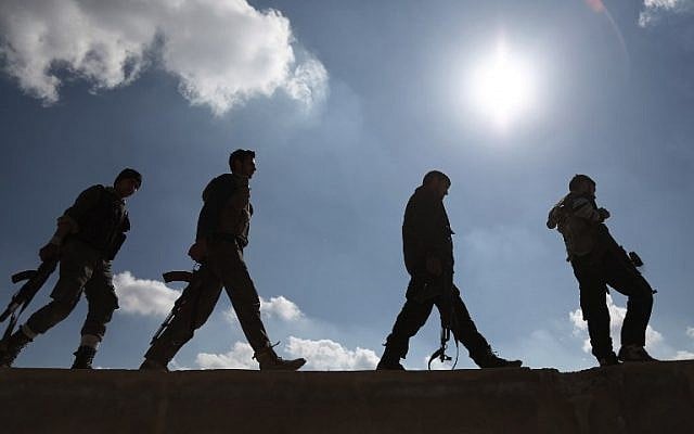 Opposition fighters belonging to Jaish al-Islam (Islam Army), the foremost rebel group in Damascus province who fiercely oppose to both the regime and the Islamic State group, walk in Tal al-Aswan in the area of the eastern Ghouta rebel bastion east of the Syrian capital, Damascus, during clashes with government forces on February 9, 2016. (AFP/AMER ALMOHIBANY)