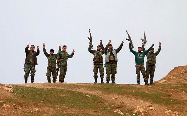 Syrian government forces raise their weapons as they patrol after taking control of the village of Kiffin, on the northern outskirts of the embattled city of Aleppo on the road leading to Gaziantep, from opposition forces on February 11, 2016. (AFP / GEORGE OURFALIAN)