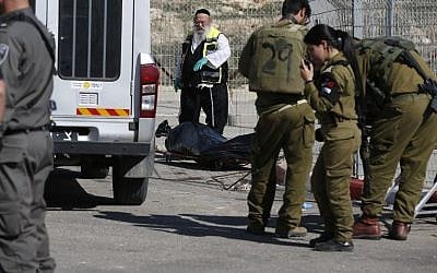 A Zaka volunteer and Israeli security forces stand next to the body of a Palestinian assailant shot dead following an attempt to stab border police at a checkpoint near Har Homa in the West Bank on February 14, 2016. (AFP/AHMAD GHARABLI)