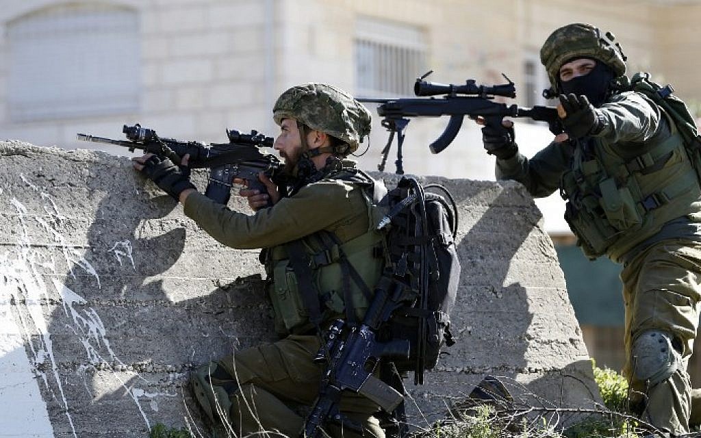 Illustrative: Israeli soldiers aim their weapons at Palestinian protesters on February 15, 2016 at the Amari Palestinian refugee camp, near the West Bank city of Ramallah, during clashes.  (AFP/ABBAS MOMANI)