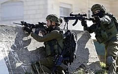 Illustrative: Israeli soldiers aim their weapons at Palestinian protesters on February 15, 2016 at the Amari Palestinian refugee camp, near the West Bank city of Ramallah, during clashes.  (AFP/ABBAS MOMANI)