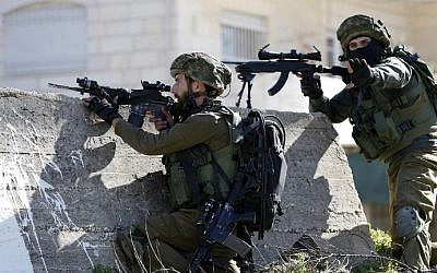 Illustrative: Israeli soldiers aim their weapons at Palestinian protesters on February 15, 2016 at the Amari Palestinian refugee camp, near the West Bank city of Ramallah, during clashes.  (AFP/ABBAS MOMANI)