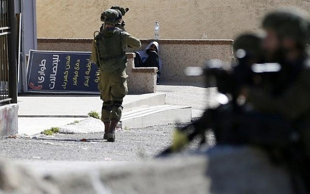 Illustrative: An IDF soldier aims his weapon at a Palestinian protester before arresting him on February 15, 2016 at the Amari Palestinian refugee camp, near the West Bank city of Ramallah (AFP / ABBAS MOMANI) Illustrative: An IDF soldier aims his weapon at a Palestinian protester before arresting him on February 15, 2016 at the Amari Palestinian refugee camp, near the West Bank city of Ramallah (AFP / ABBAS MOMANI)
